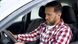 Hearing Weird Car Noises | ABS Unlimited in Fairfax, VA. Image of a male driver trying to figure out what’s the noise he is hearing inside his car.