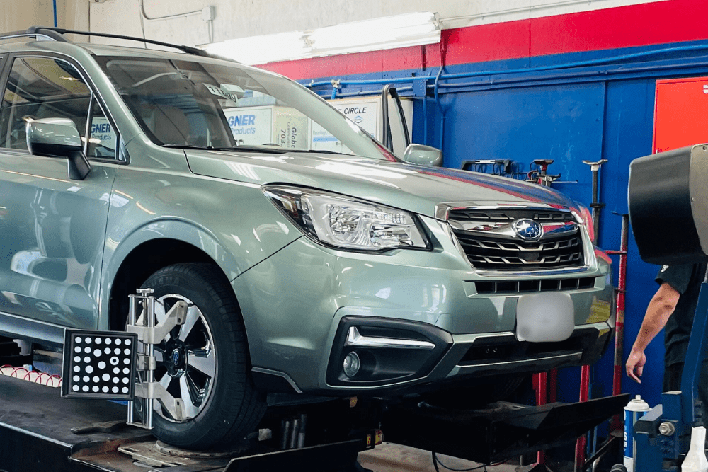 front wheel alignment, auto repair in Fairfax, VA at ABS Unlimited Auto Repair , Image of a light green Subaru Forester on an alignment lift.