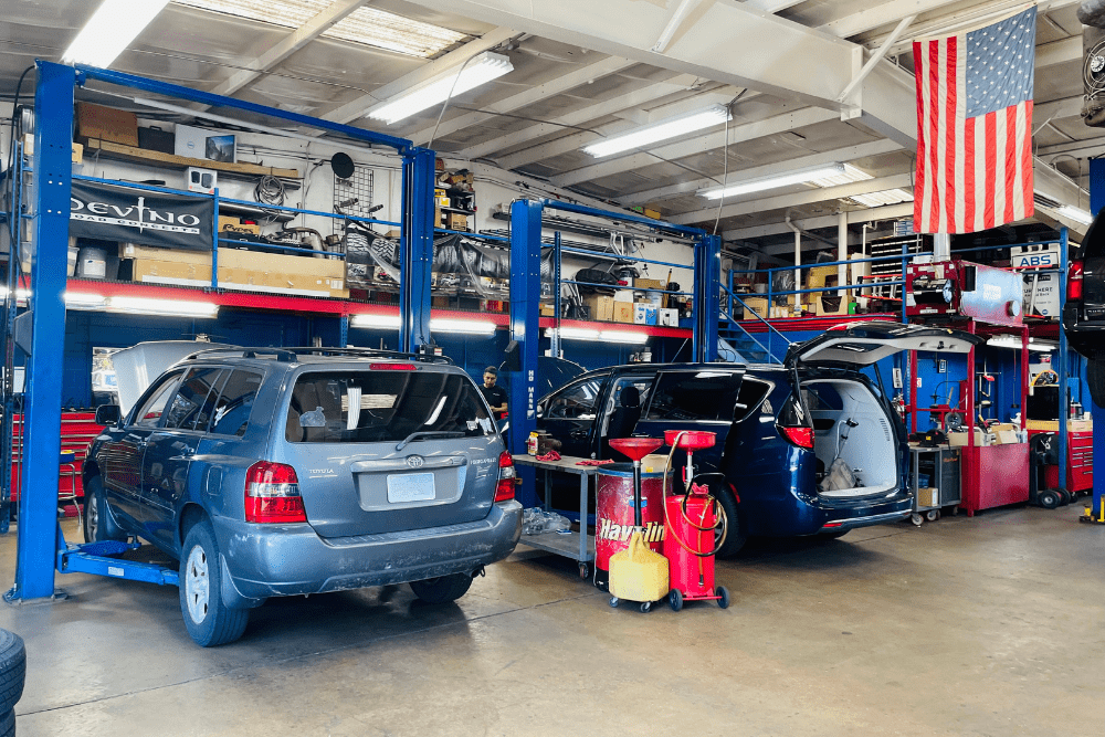 Back-to-school car safety check in Fairfax, VA by ABS Unlimited Auto Repair. Image of multiple vehicles in a well-equipped service bay with lifts, tools, and technicians at work.